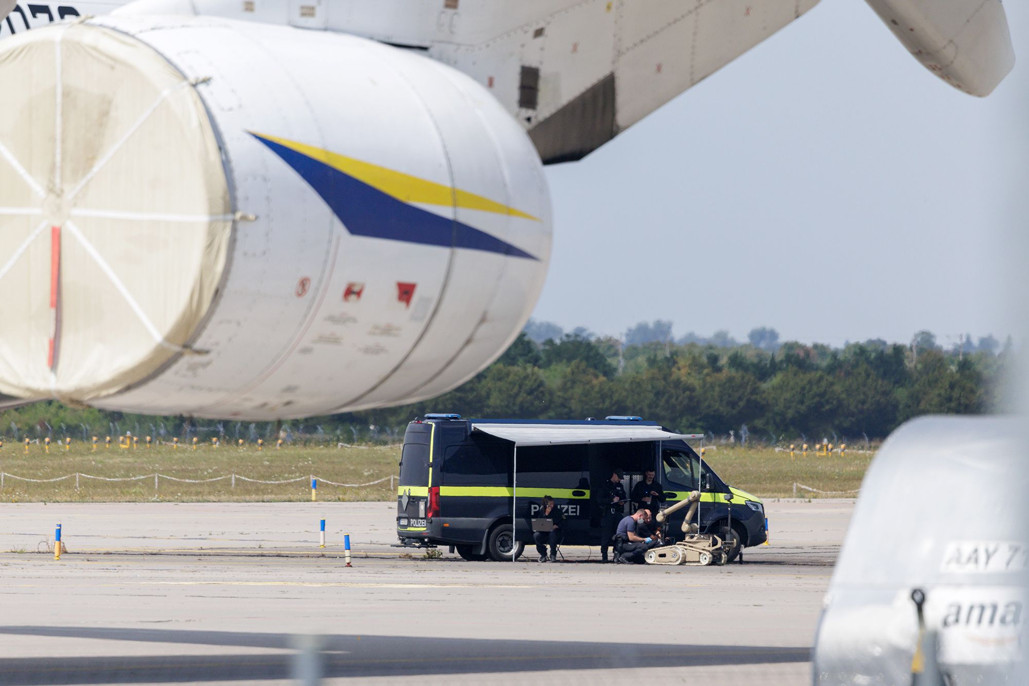 LEIPZIG, GERMANY - AUGUST 5: Police investigators work on the tarmac with a robot that is capable, amongst other things, of defusing explosives, near to Ukrainian Antonov cargo plane at Leipzig/Halle Airport on August 5, 2026 near Leipzig, Germany. Airport workers reportedly discovered a drone yesterday on the tarmac near an Antonov at the airport that was equipped with an explosives detonator and an unidentified substance. Additionally, a DHL cargo plane that took off from the airport late last night collided with a small object, causing minor damage. (Photo by Jens Schlueter/Getty Images)