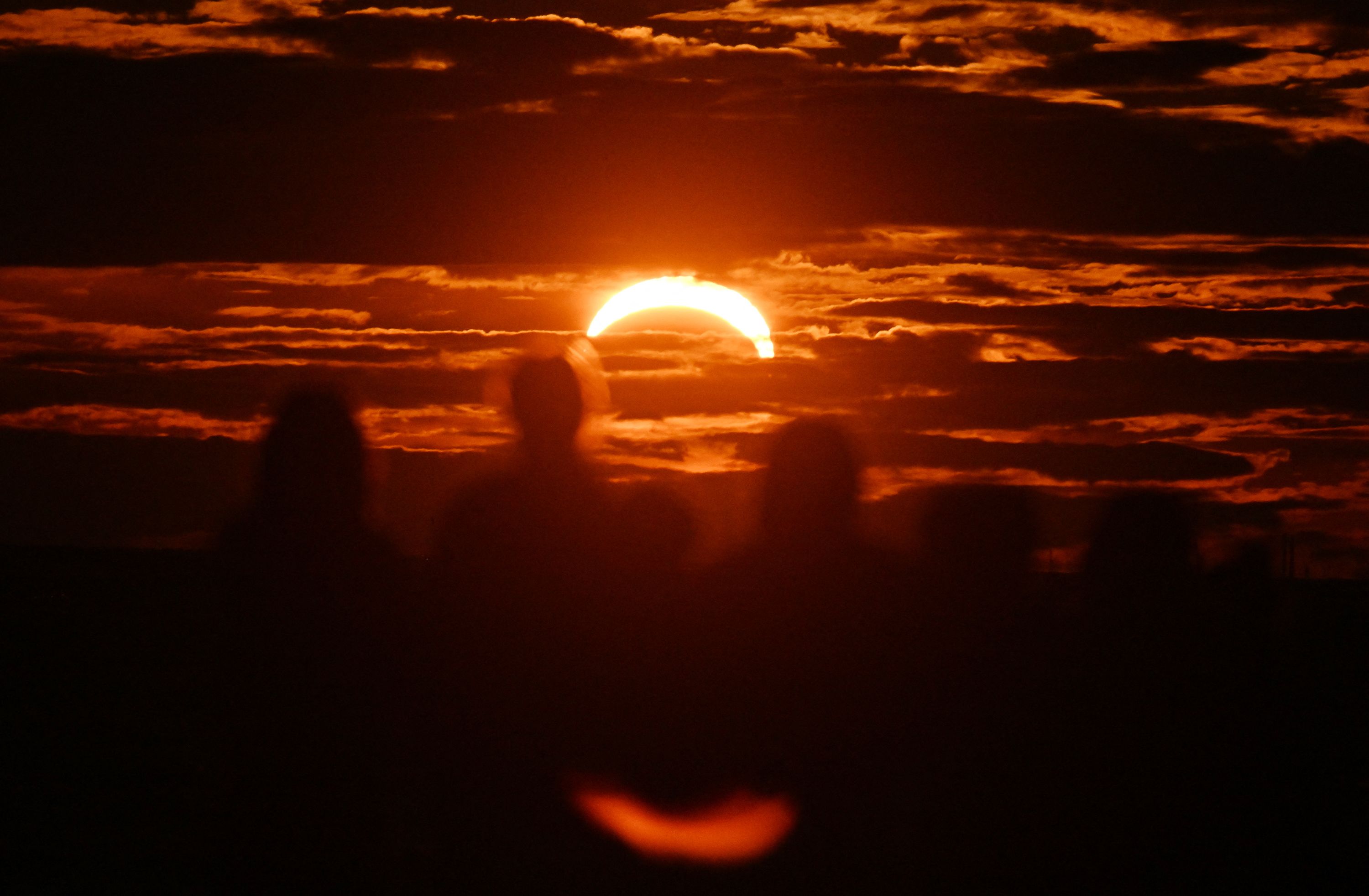 The moon passes in front of the sun as it sets during a partial solar eclipse in Saint Petersburg on August 12.