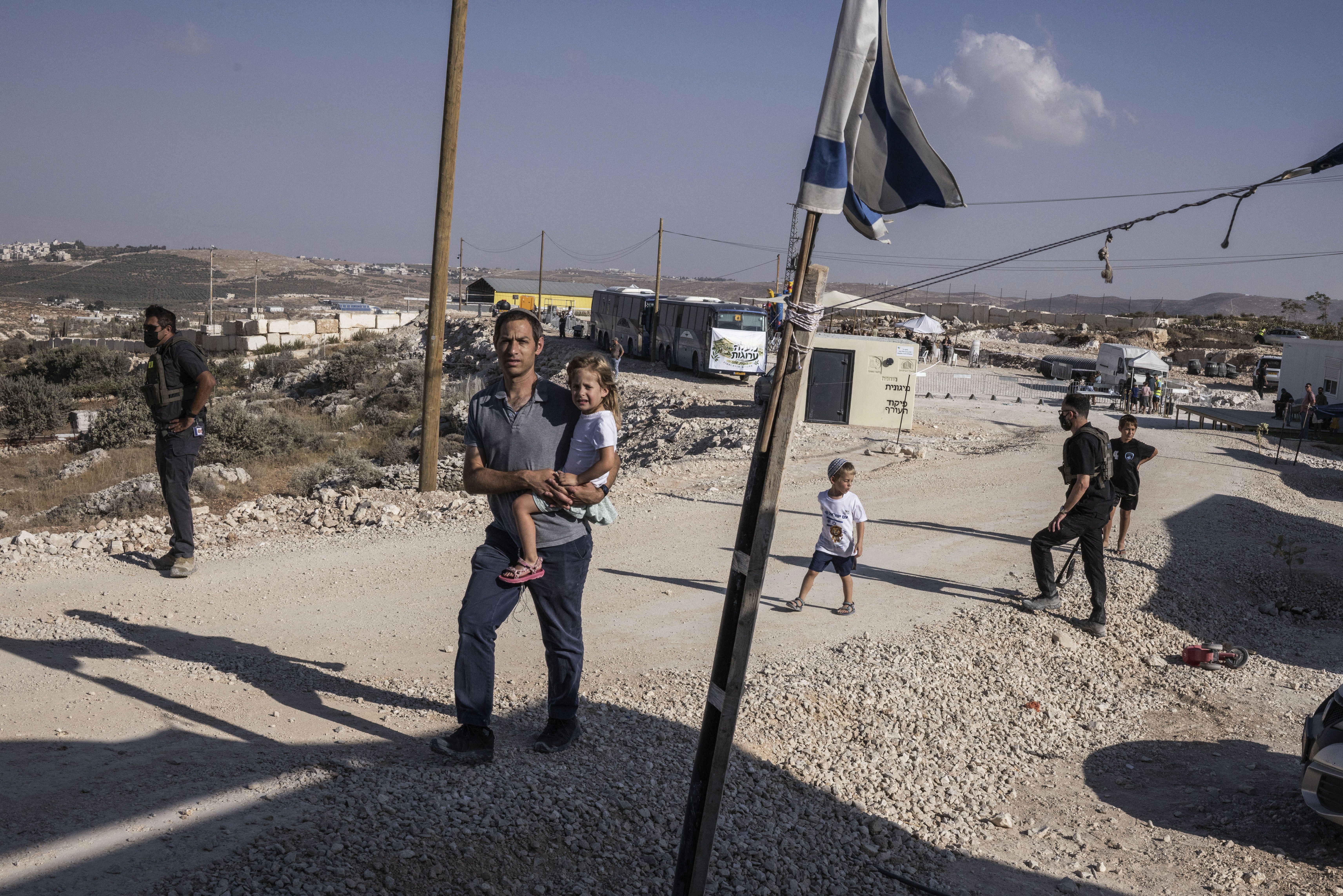 A man carries his child through a new Israeli settlement of Maale Arugot during its official inauguration ceremony in Gush Etzion, in the occupied West Bank on September 2, 2026.