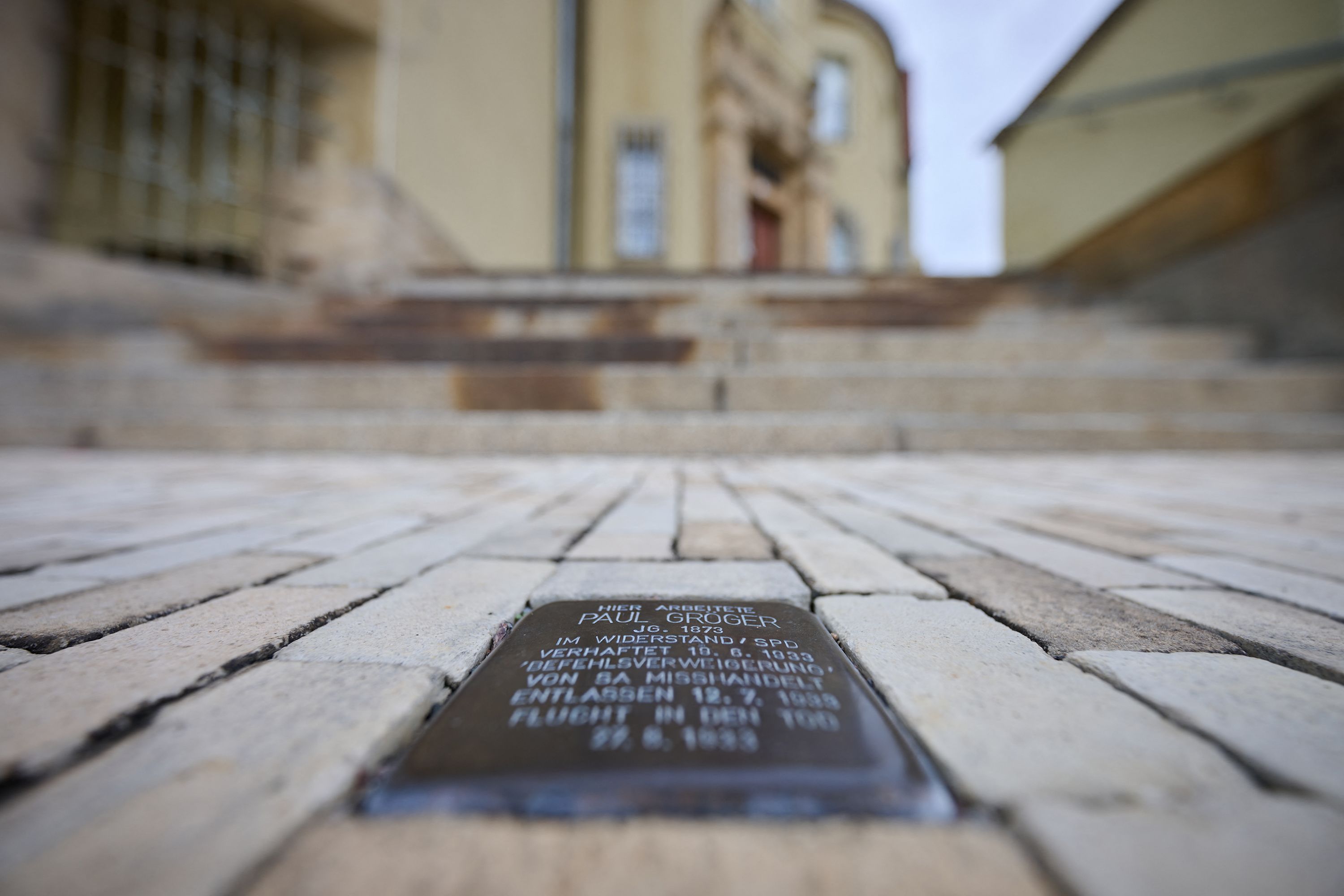 25 September 2026, Saxony, Heidenau: A Stolperstein commemorating Nazi victim Paul Gröger is embedded in the sidewalk in front of City Hall. The city council of Heidenau, near Dresden, no longer permits new Stolpersteine to be installed on city streets. On September 24, 2026, the city council of the Saxon city approved a motion to that effect, proposed by the AfD and CDU, by a majority vote. Stumbling stones as a form of remembrance have existed since the 1990s and are found in many European countries.