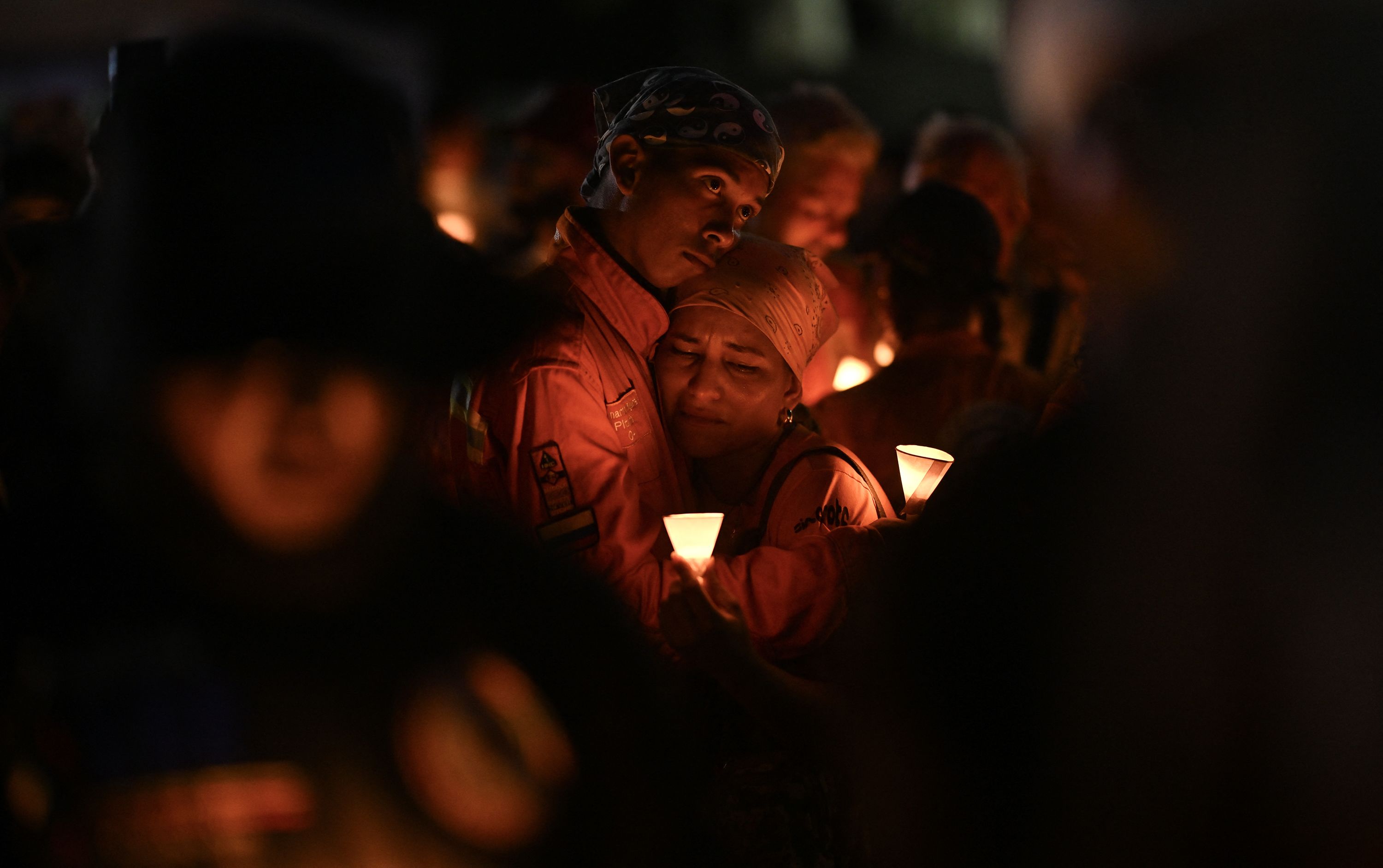 People hold candles during a vigil and prayer service called "Beam of Light," in Caraballeda, La Guaira state, Venezuela, on October 2, marking 100 days since the twin earthquakes that struck Venezuela on June 24, killing and displacing thousands of people.