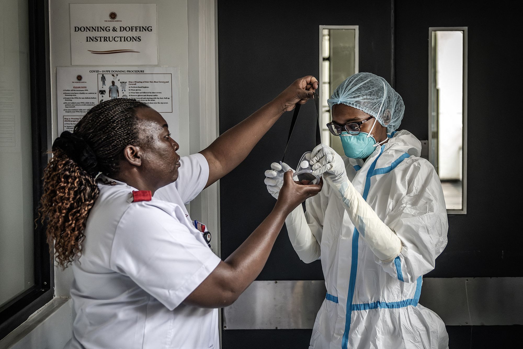 A nurse is assisted by a colleague in donning personal protective equipment (PPE) at an isolation facility prepared to receive potential Ebola patients during a media visit to Nairobi Hospital in Nairobi on October 7, 2026. Kenya has reported its first-ever Ebola death, the health minister announced on October 6, 2026, after a Kenyan man who had been living in the Democratic Republic of Congo died after returning to the country. (Photo by Luis TATO / AFP via Getty Images)