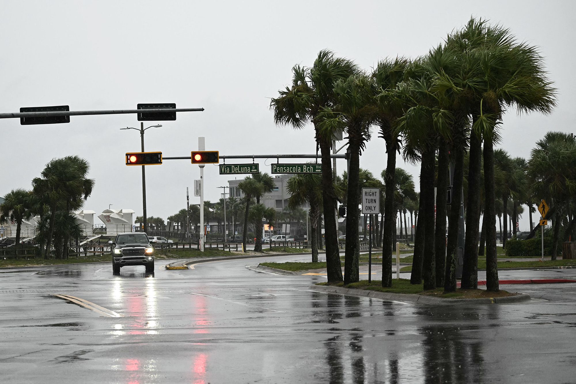 A car drives along a road in Pensacola Beach, Florida, on October 9, 2026, as Hurricane Isaias moves north toward the Florida Panhandle. Hurricane Isaias intensified to Category 2 in the Gulf of Mexico's warm waters on Thursday as it churned toward the southern United States, the National Hurricane Center (NHC) said. The first hurricane of the Atlantic season, Isaias is forecast to make landfall in Florida, Alabama or Mississippi overnight Friday to Saturday, according to the NHC.