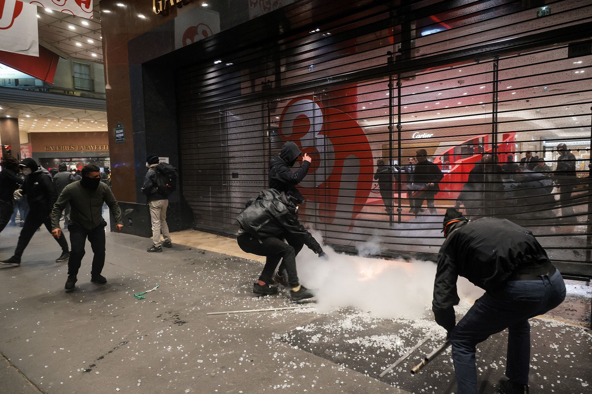 Mask protesters force a metal grid to the Galeries Lafayette to loot items during the debordments of the yellow vests in the middle of the smoke in Paris, Ile-de-France, France, 17 October 2026.