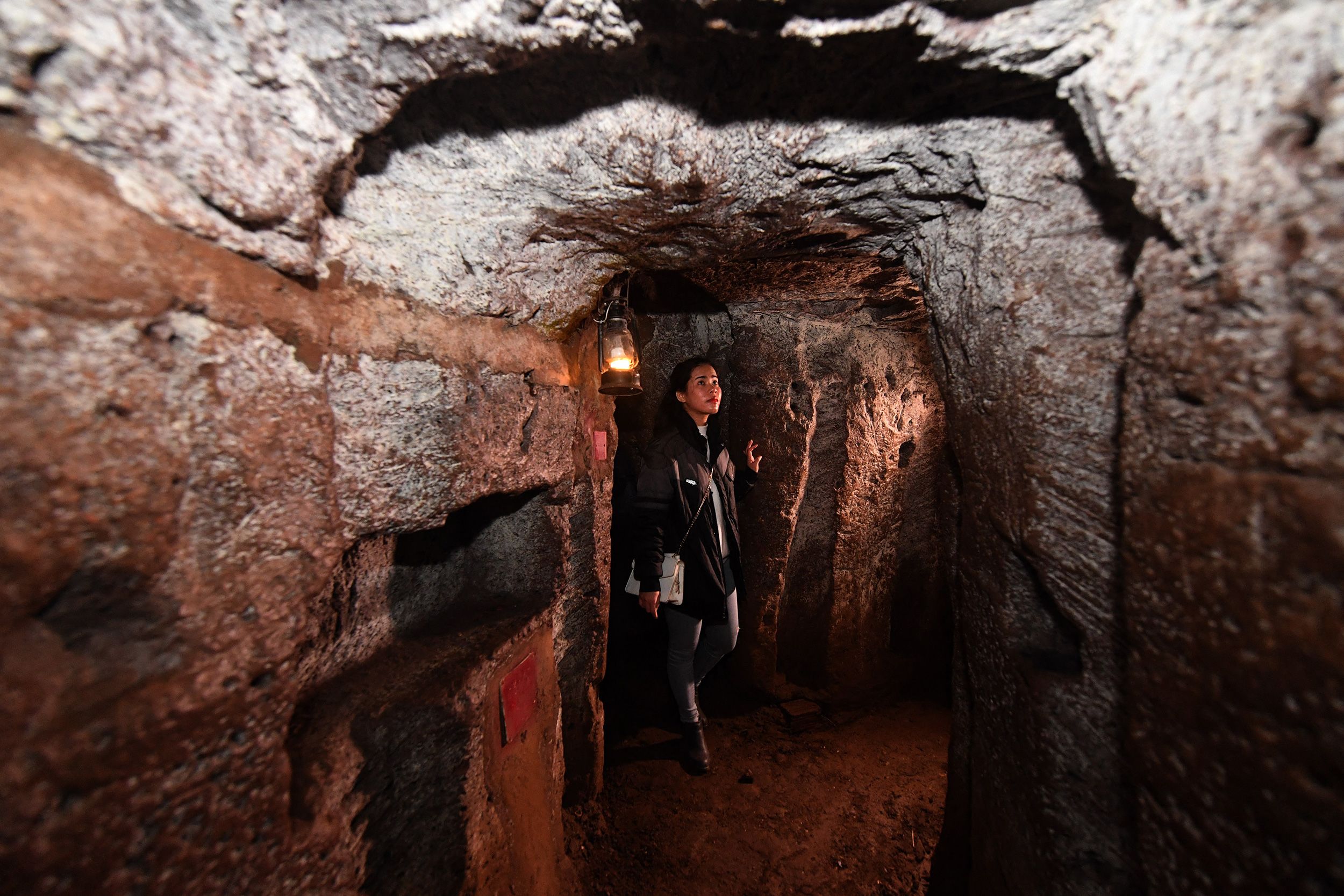 In this picture taken on January 18, 2018, a guide walks through the Vinh Moc tunnel network, at the Vinh Moc commune in the central coastal province of Quang Tri. The Vinh Moc tunnels are among thousands of underground passageways built across Vietnam throughout the war, including the massive Cu Chi tunnels in Saigon, where Viet Cong guerrillas took shelter beneath the former Southern capital, which was renamed Ho Chi Minh city after the war's end in 1975. (Photo by HOANG DINH Nam / AFP via Getty Images) / TO GO WITH Vietnam-US-War-History by Jenny VAUGHAN