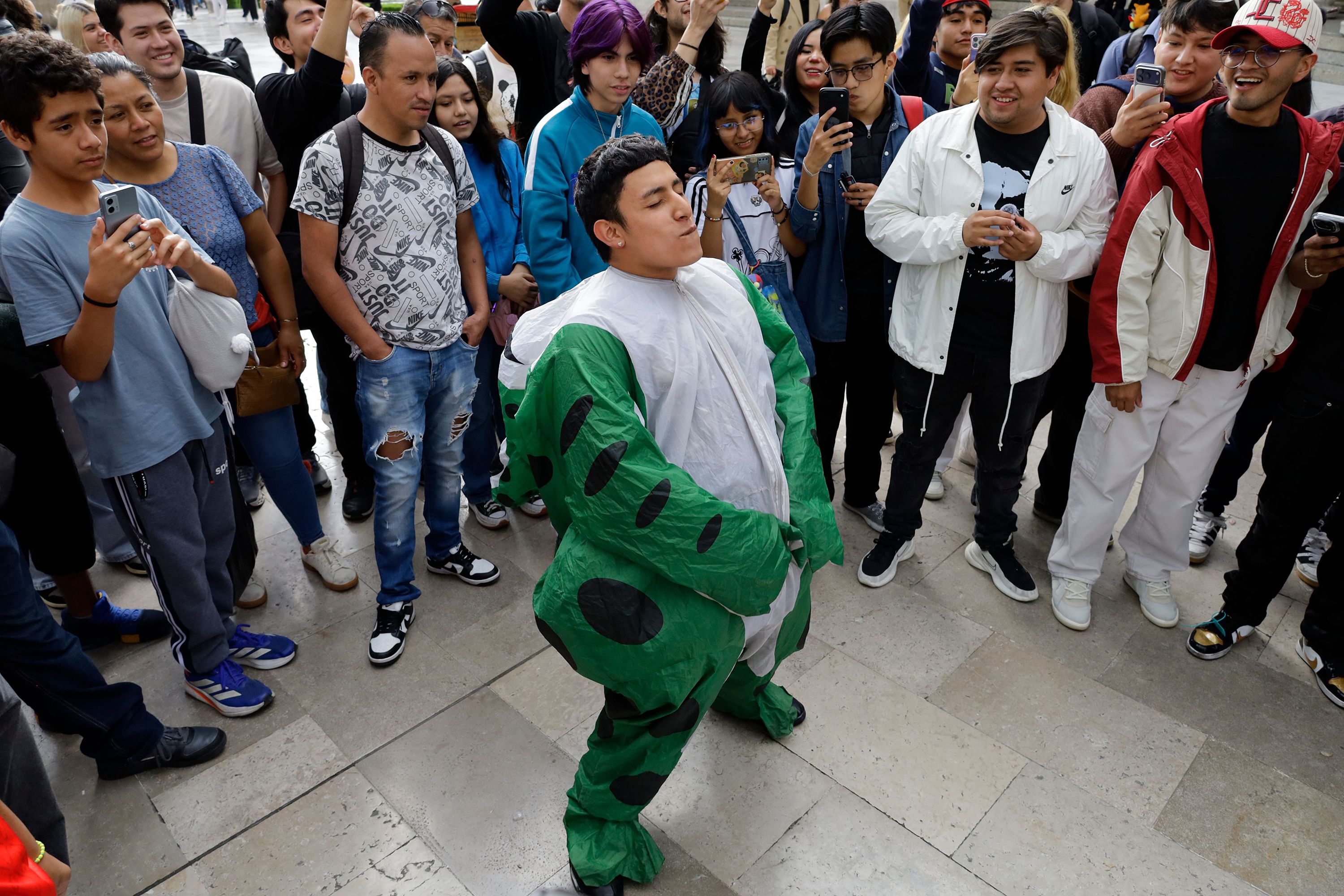 A young person dressed as a frog takes part in the first ''Aura Farming'' battle on the esplanade of the Palace of Fine Arts in Mexico City, Mexico, on August 20, 2026. Participants gather for an open-air performance involving an exchange of movements, dance, acrobatics, physical feats, and gestures, each adapted to the individual's personality.