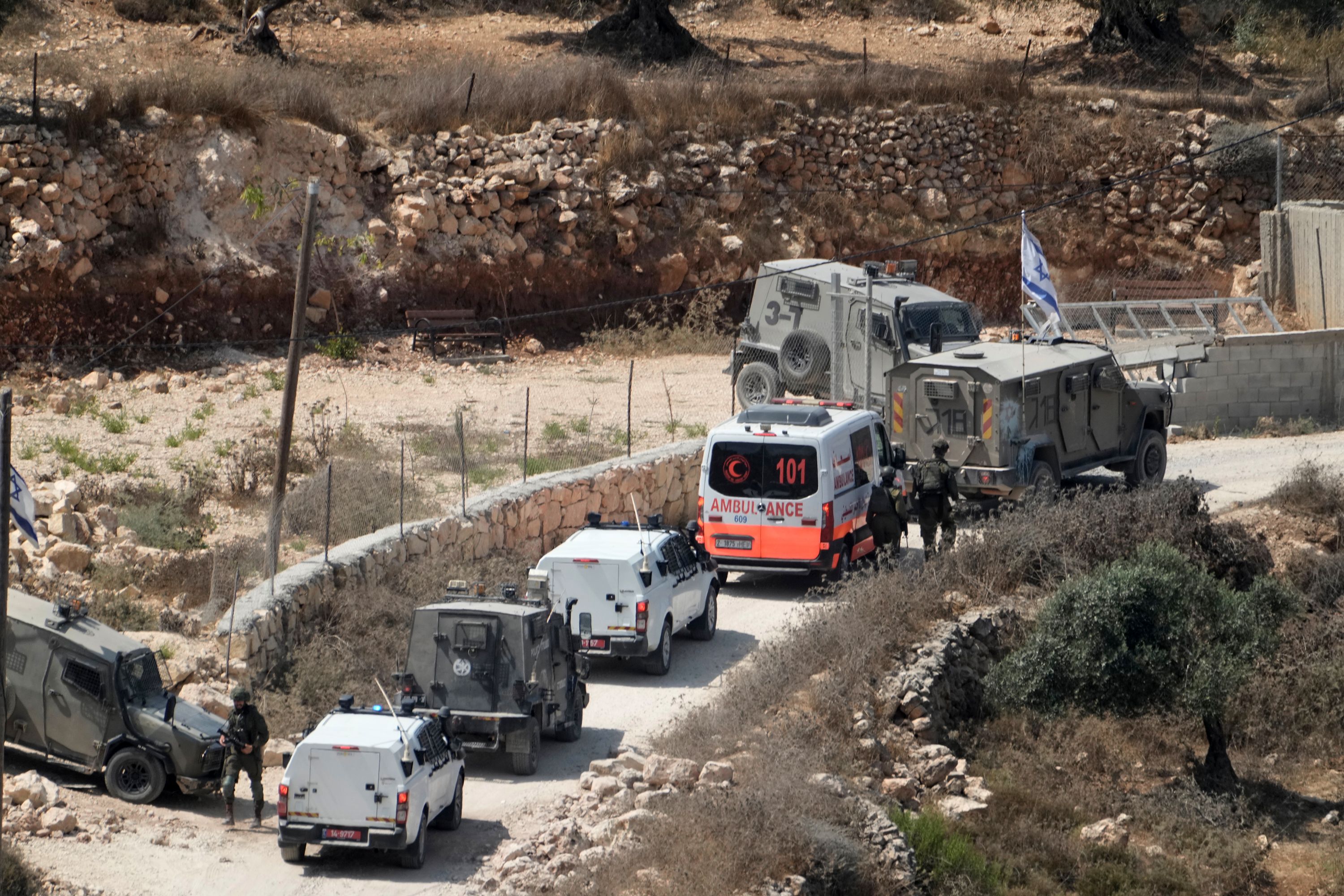 Israeli soldiers secure a building under construction as ambulances evacuate injured Palestinians following an attack by Israeli settlers in the occupied West Bank village of Qusra, on August 29. (AP Photo/Majdi Mohammed)
