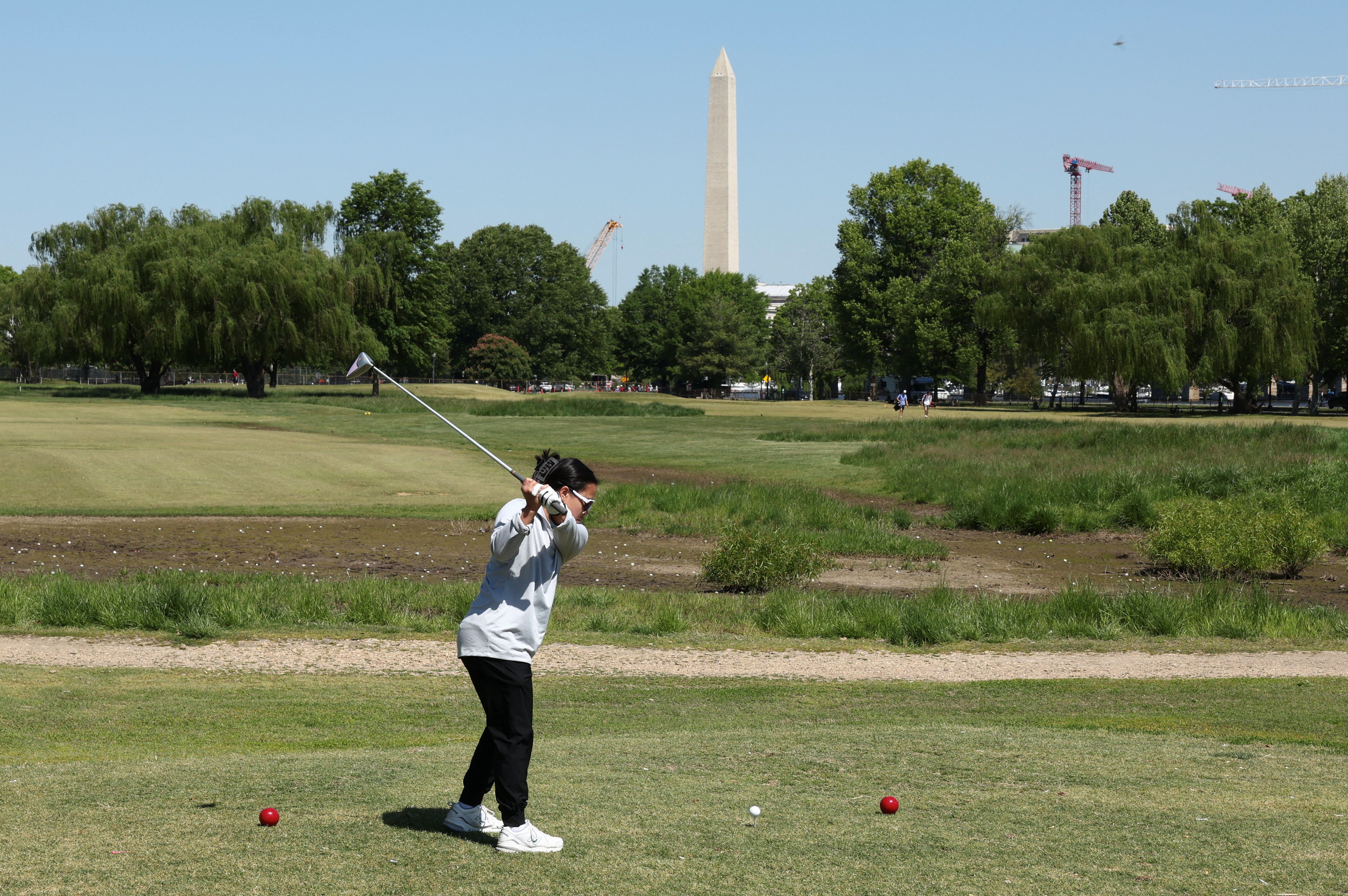 With the Washington Monument in the background, a golfer tees off at East Potomac Golf Course, whose future is in the courts as the Trump administration plans to take over operations and close it down to begin maintenance work, in Washington, D.C., U.S., May 4, 2026. REUTERS/Kevin Lamarque