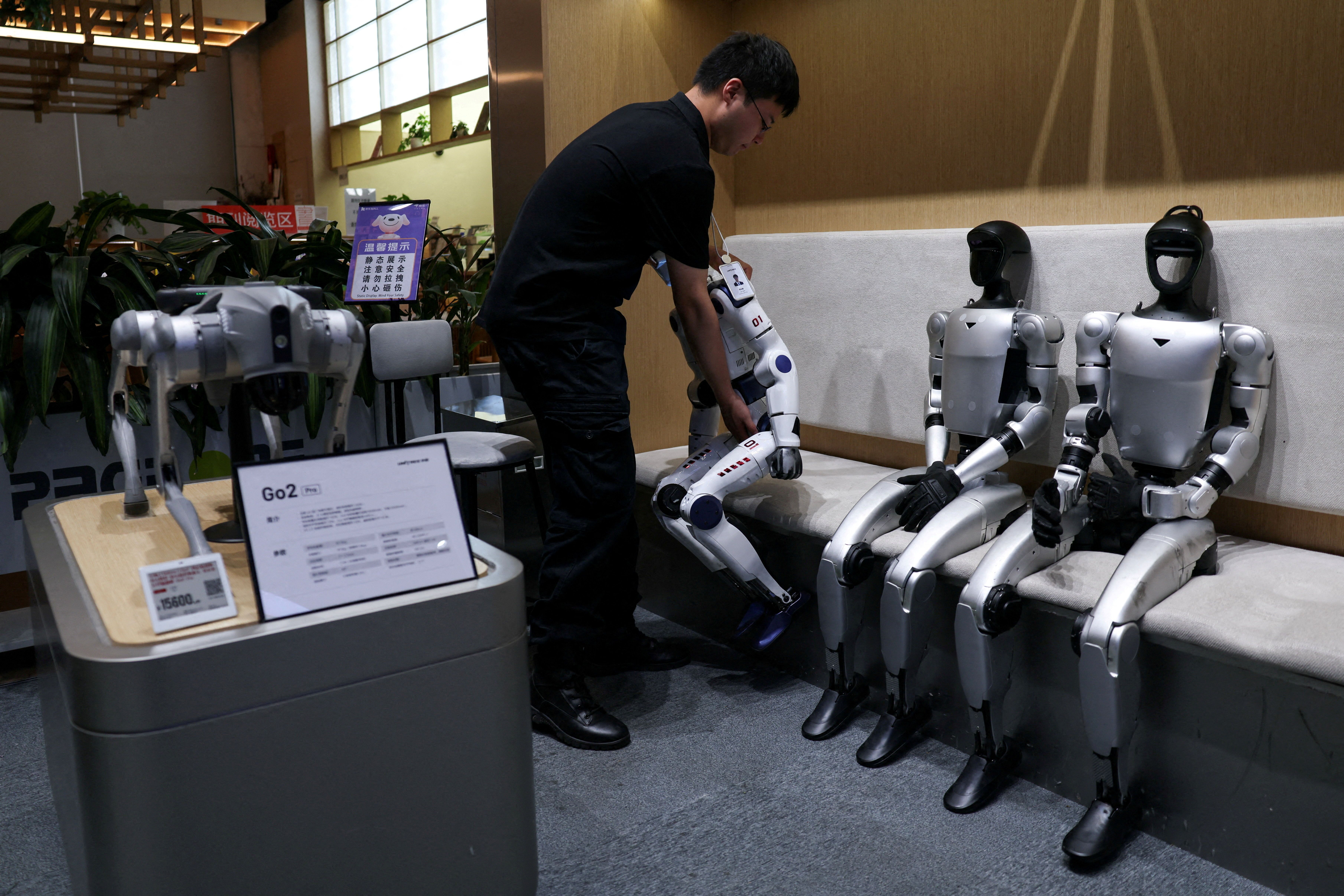 A staff member places a Unitree's R1 humanoid robot back in its seat at a Unitree store in Beijing, China, on August 1, 2026.
