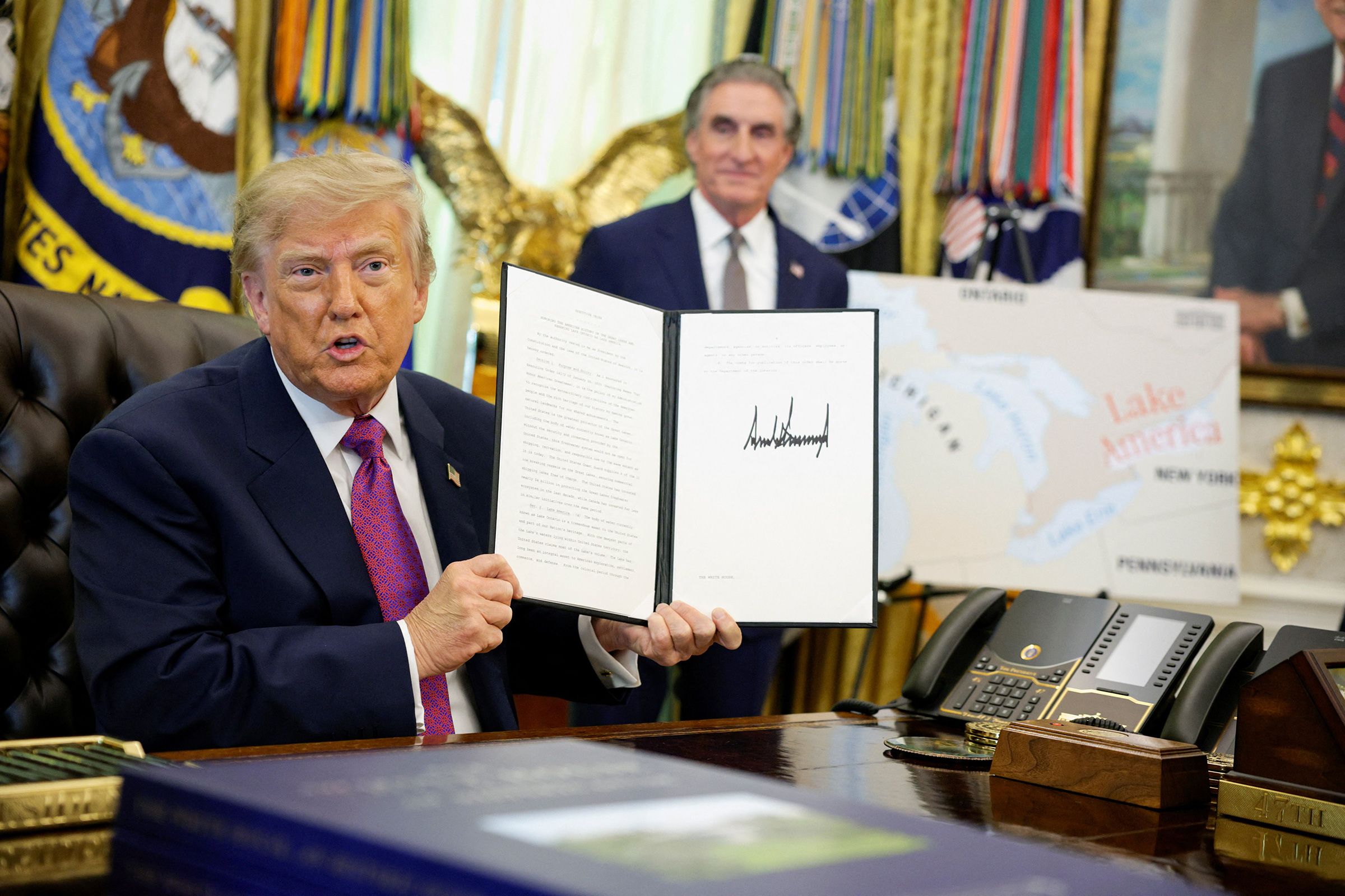 US President Donald Trump holds up an executive order renaming Lake Ontario as Lake America after signing it at the Oval Office of the White House in Washington, DC, on August 27.