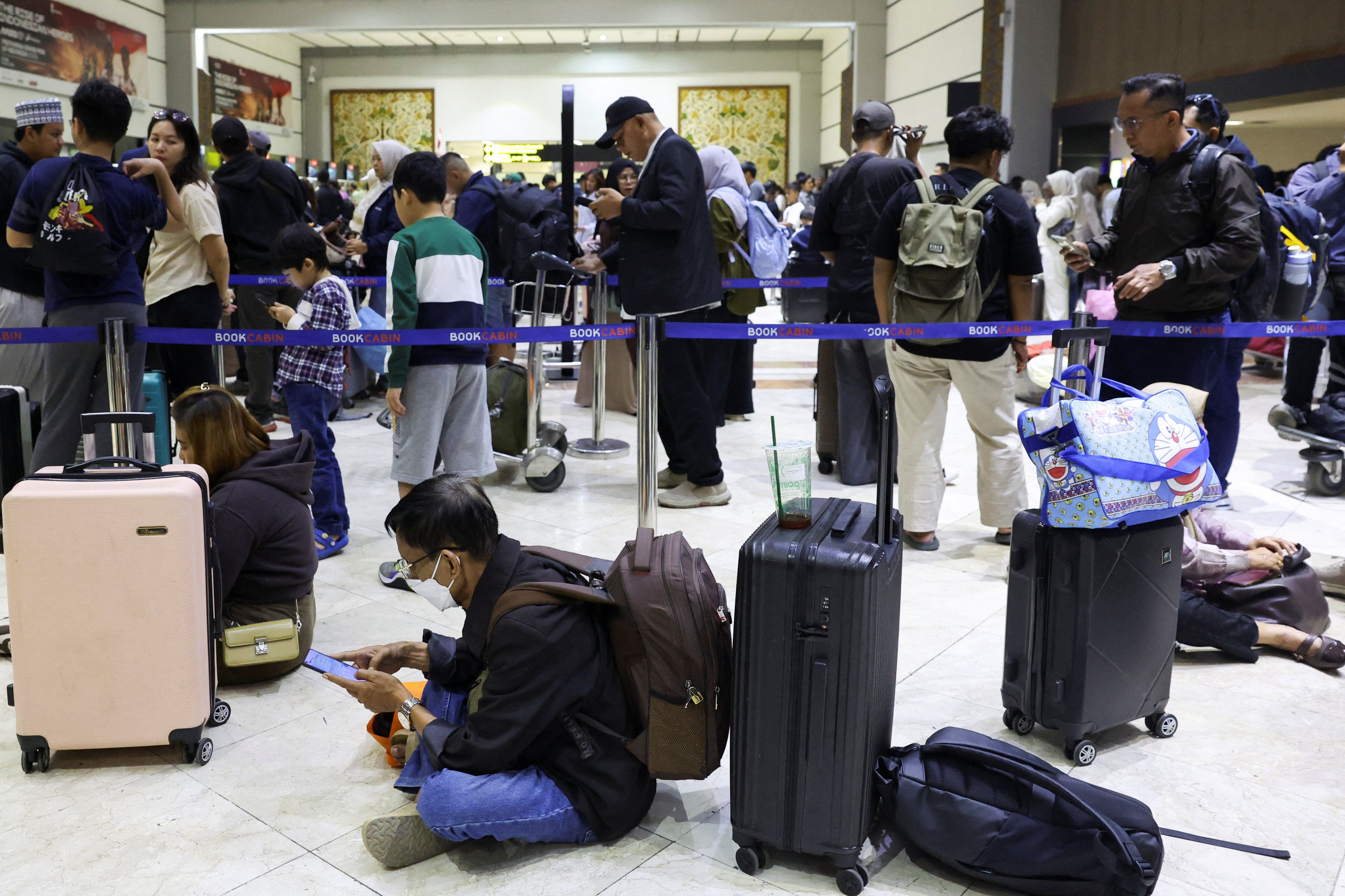 Stranded passengers wait at check-in area as Soekarno Hatta International Airport closed its operations due to the eruption of the Mount Anak Krakatau volcano, in Tangerang, near Jakarta, Indonesia.