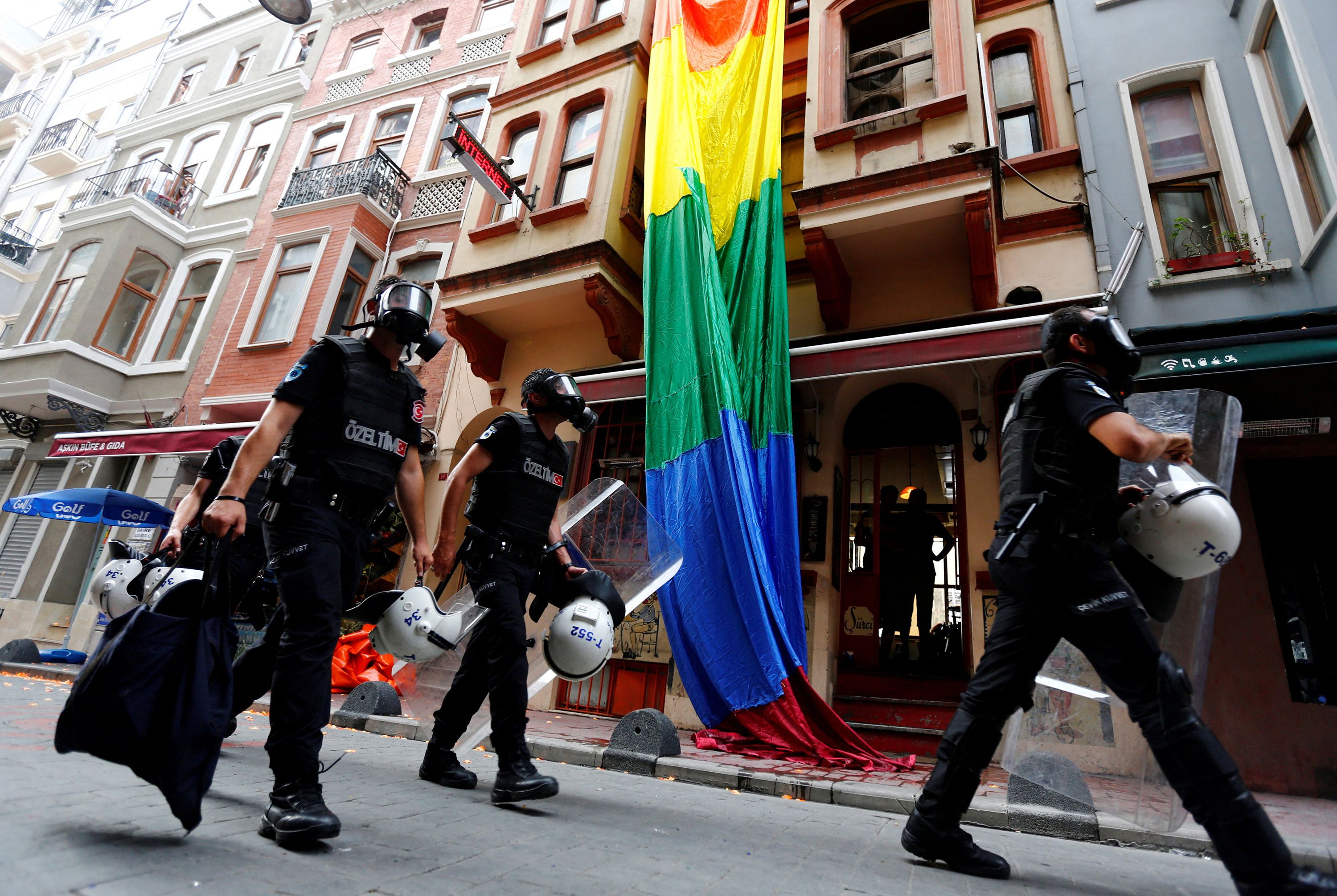 Riot police, with a rainbow flag in the background, chase LGBT rights activists as they try to gather for a pride parade, which was banned by the governorship, in Istanbul, Turkey, June 26, 2016.