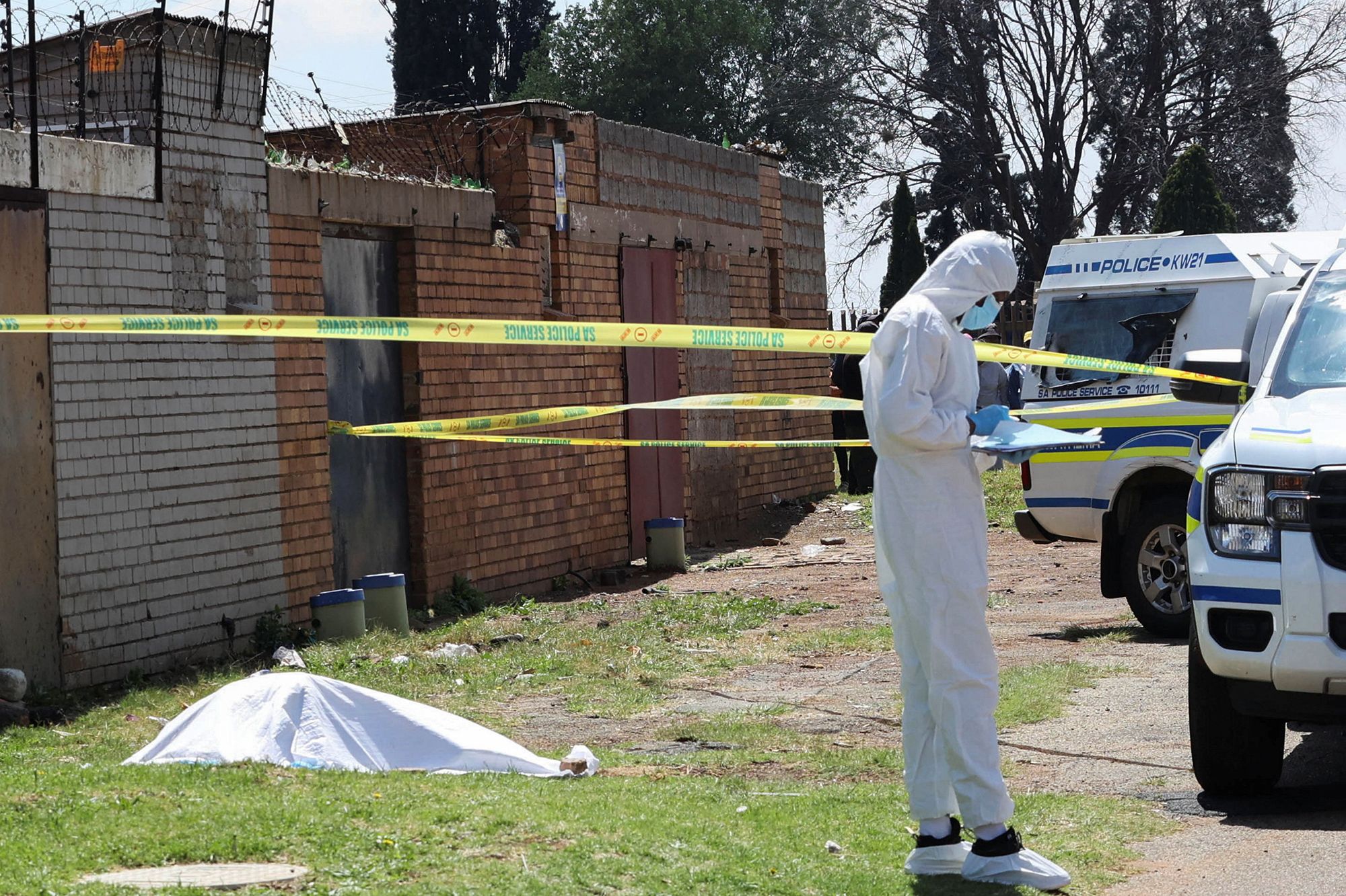 A forensic investigator works near a cordoned-off crime scene where the body of one of nine women killed was found in Ekurhuleni, east of Johannesburg, South Africa, on September 15, 2026.