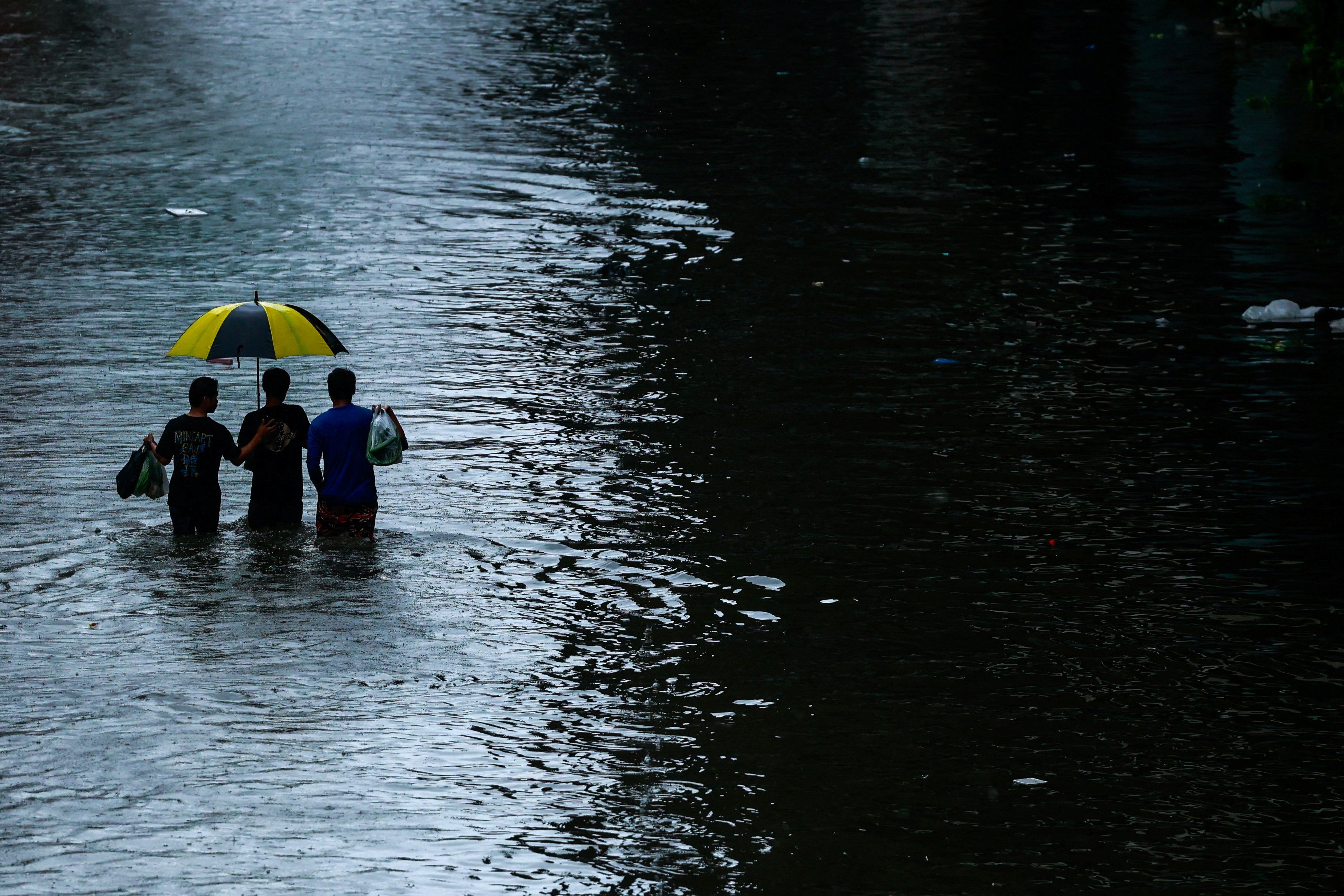 People wade through a flooded street during heavy rain in Bangkok, Thailand, on September 26, 2026.