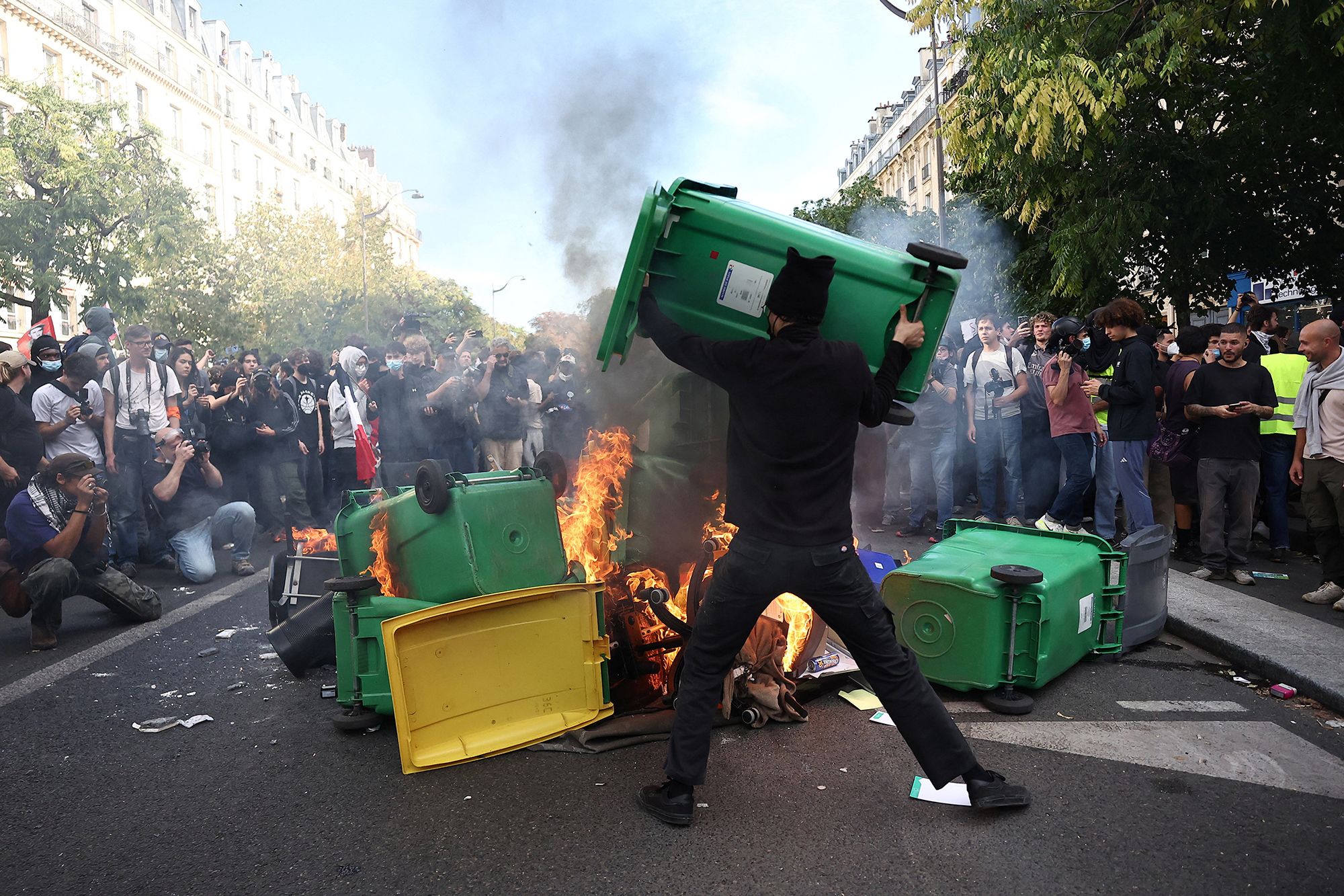 A protester throws a garbage bin into burning objects during a demonstration by high school and university students, in Paris on Tuesday, as part of a nationwide day of protests over overcrowded classrooms, teacher shortages and dilapidated school buildings.