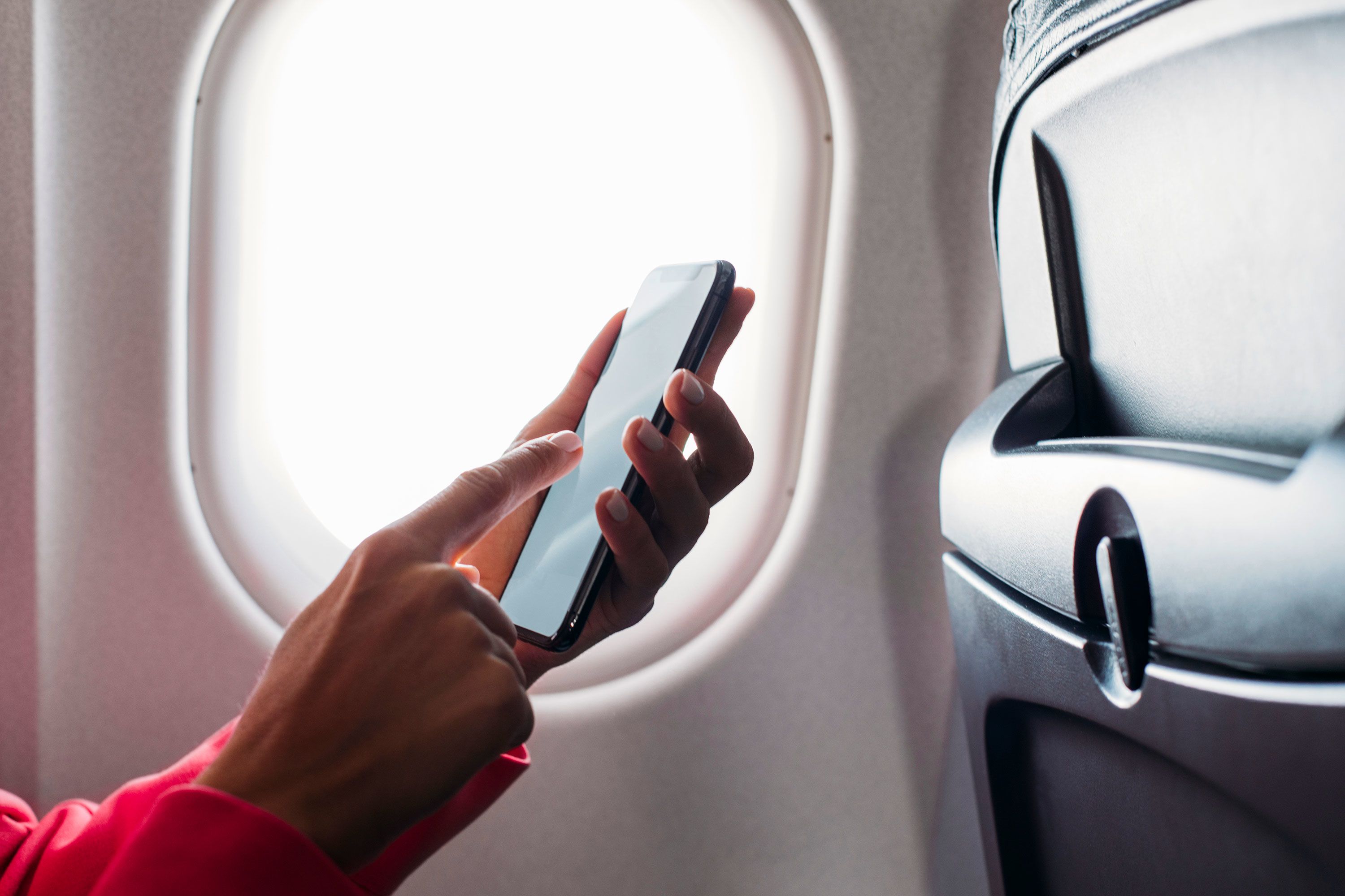 Close up shot of an unrecognisable woman's hand while holding a phone in an airplane