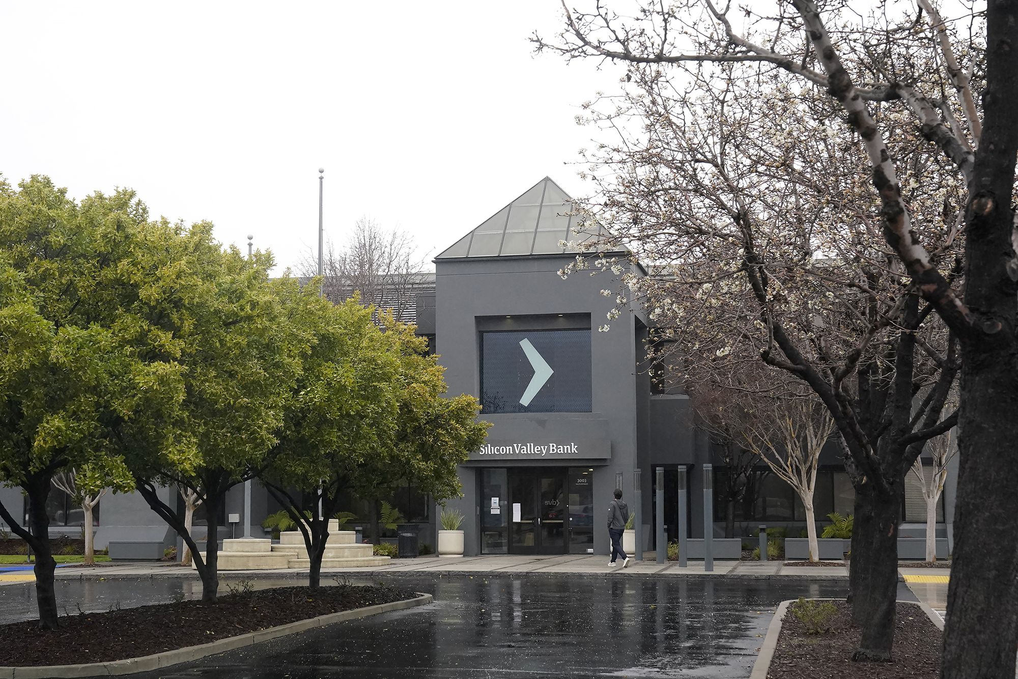 A person walks toward an entrance to Silicon Valley Bank in Santa Clara, Calif., Friday, March 10, 2023. 