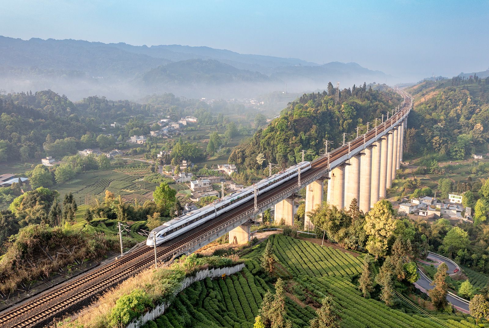 A bullet train runs through a tea garden on April 12, 2023 in Yan'an, Sichuan Province of China.