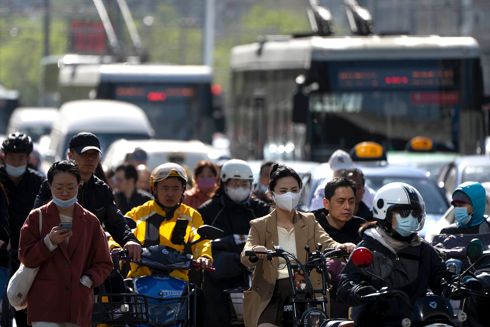 Commuters cross an intersection in the central business district during the morning rush hour in Beijing, Tuesday, April 18, 2023.