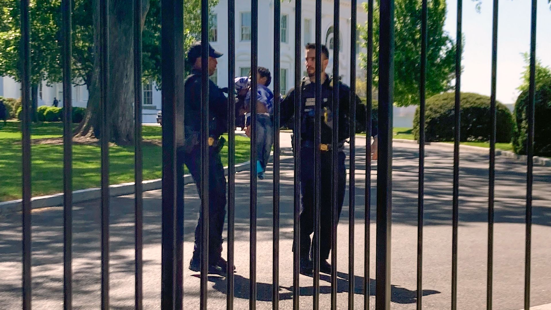 Secret Service uniformed division police officers carry a young child who crawled through the White House fence on Pennsylvania Avenue in Washington, Tuesday, April 18.